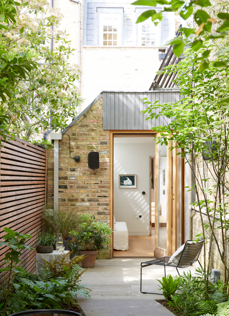 Идеи небольшого сада - городской внутренний дворик-сад с решетчатым деревянным забором, кирпичной стеной и каменным полом