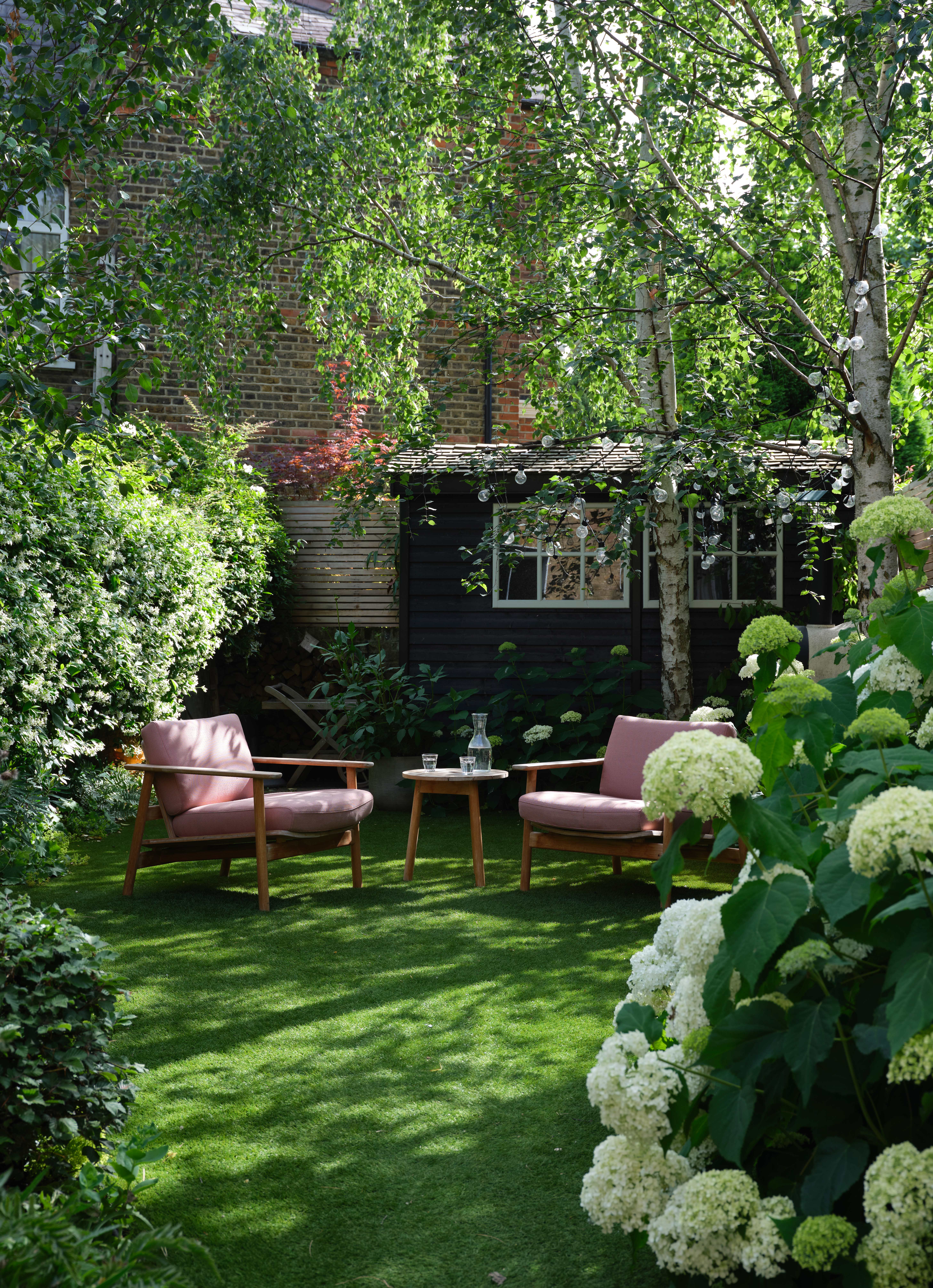 Небольшой сад с газоном, сидячими местами на открытом воздухе и навесом