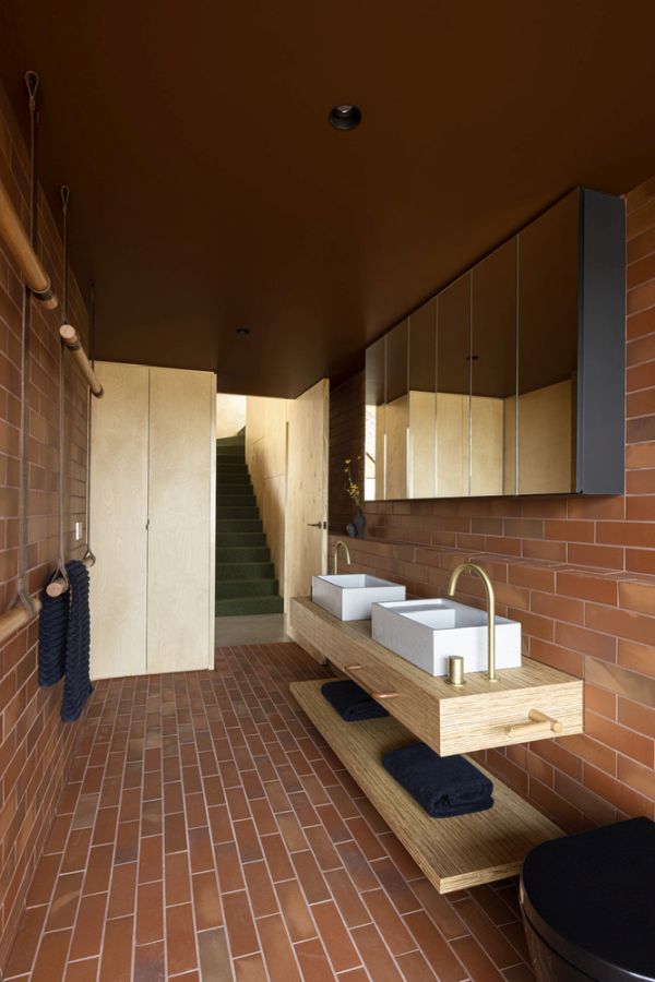 Рисунок из красного кирпича и коричневый потолок придают ванной комнате теплый и уютный вид.
