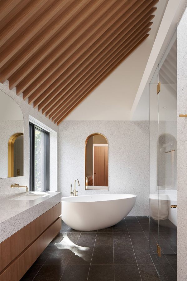 Гостевая ванная комната на верхнем этаже украшена элегантной золотой отделкой и овальной отдельно стоящей ванной.