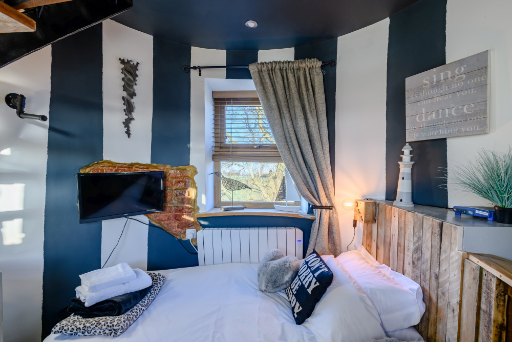 Одна из спален с бело-темно-синими полосатыми стенами и приятной морской атмосферой.