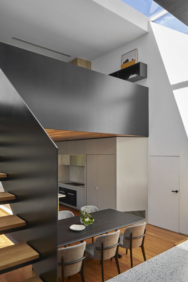 Скульптурная парящая лестница обрамляет кухню и столовую и ведет на верхний уровень.