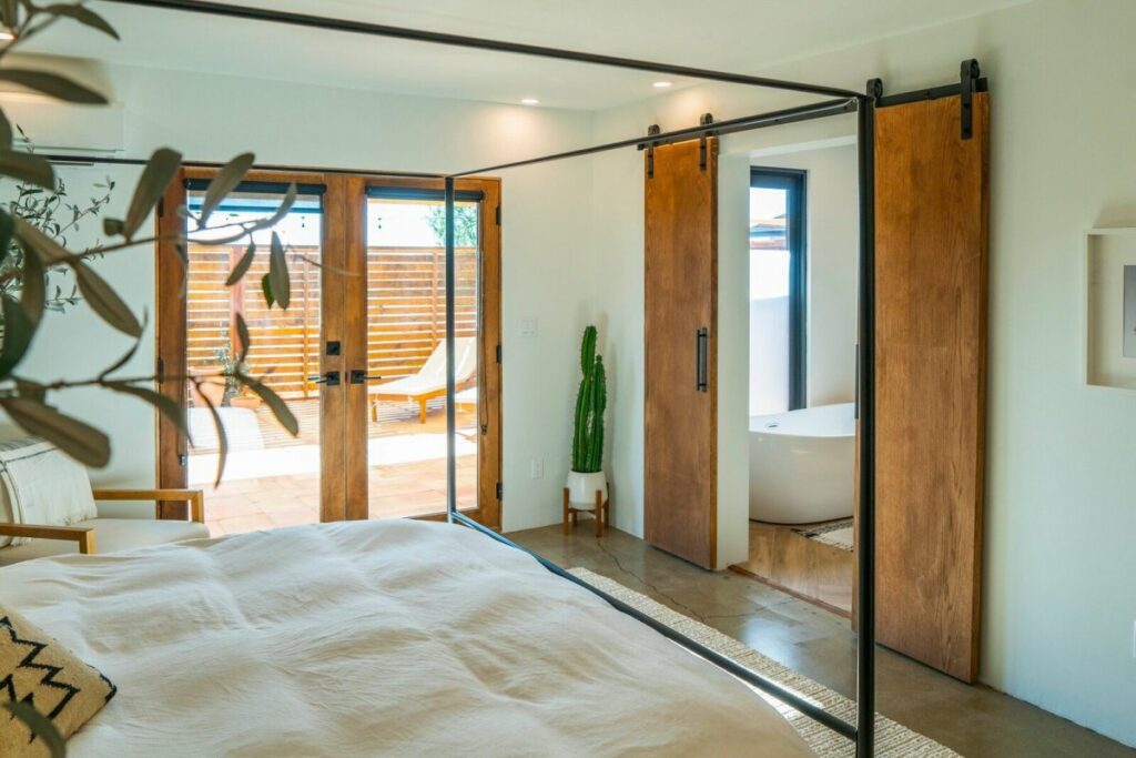 Комплект раздвижных дверей сарая отделяет спальню от ванной комнаты.