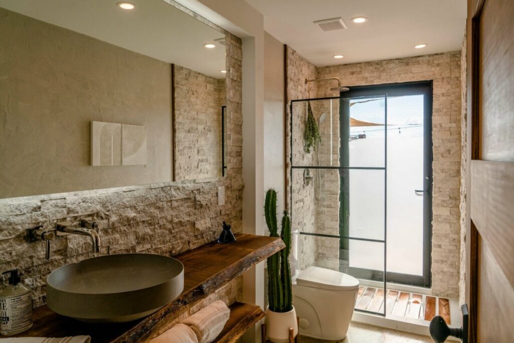 Гостевая ванная комната имеет очень естественный и фактурный вид благодаря каменной плитке.