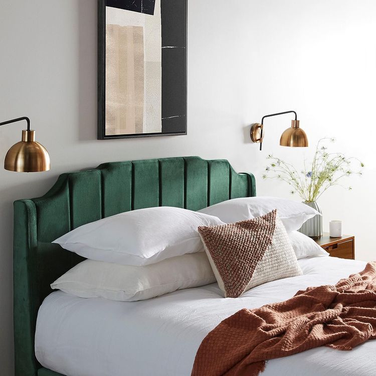зеленая кровать и золотые лампы на стене